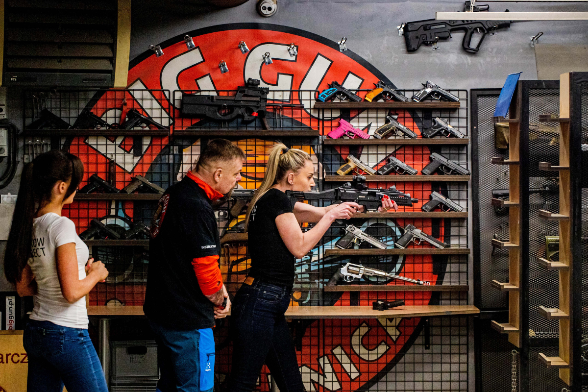 Shooting instructor in Krakow teaches tourists how to aim and hold a rifle at the shooting range.