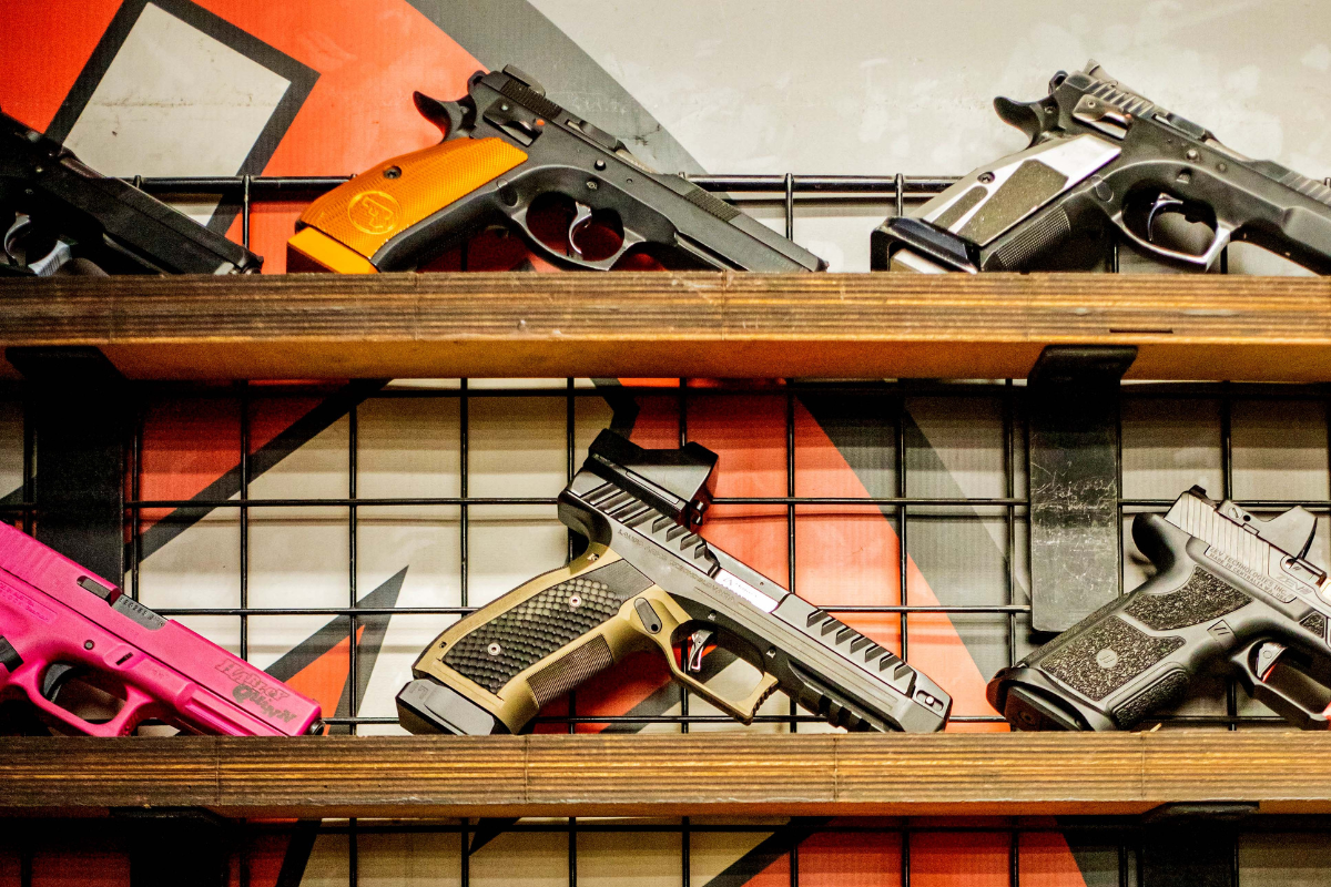 Various handguns and pistols neatly arranged on display shelves at a Krakow shooting range.