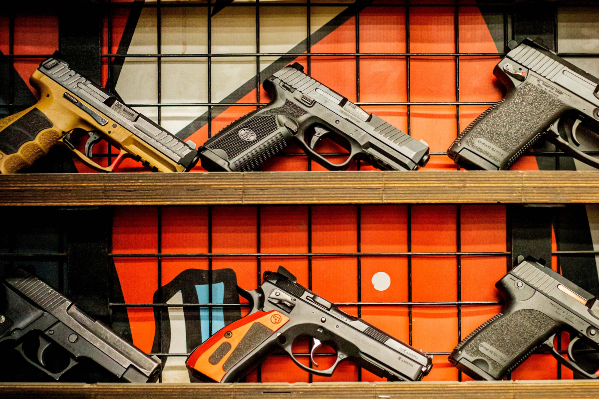 Handguns and pistols arranged on metal shelves at a Krakow shooting range in Krakow, ready for use by visitors.