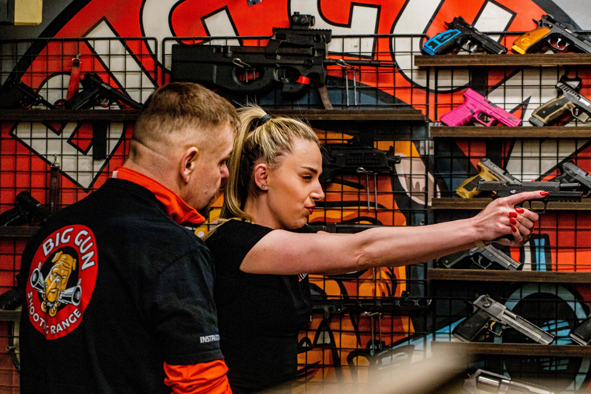 Shooting instructor in Krakow showing a student how to aim and safely shoot a pistol at the shooting range.