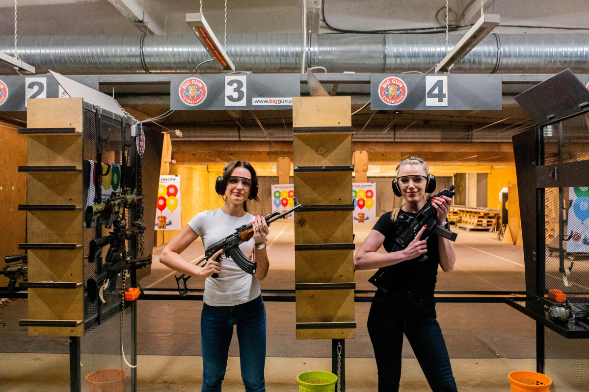 Tourists at Krakow shooting range standing at their lanes, preparing to shoot with safety gear on.