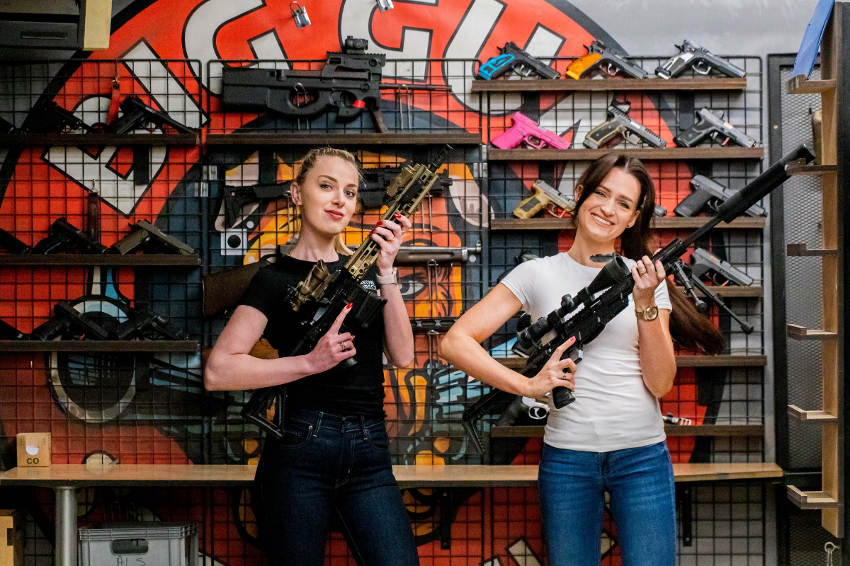 Two tourists posing with rifles at Krakow shooting range, ready for target practice and shooting experience.