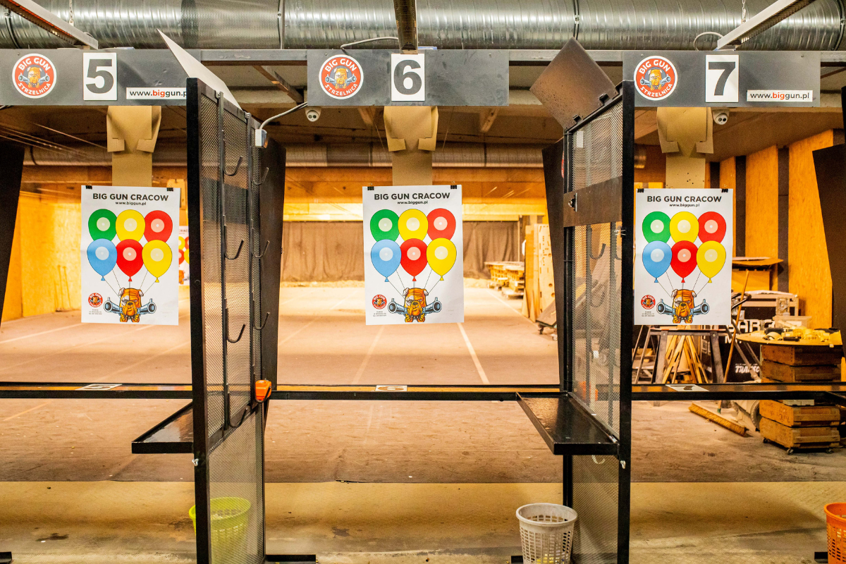 Indoor shooting range in Krakow with numbered shooting stalls and colorful paper targets ready for practice.