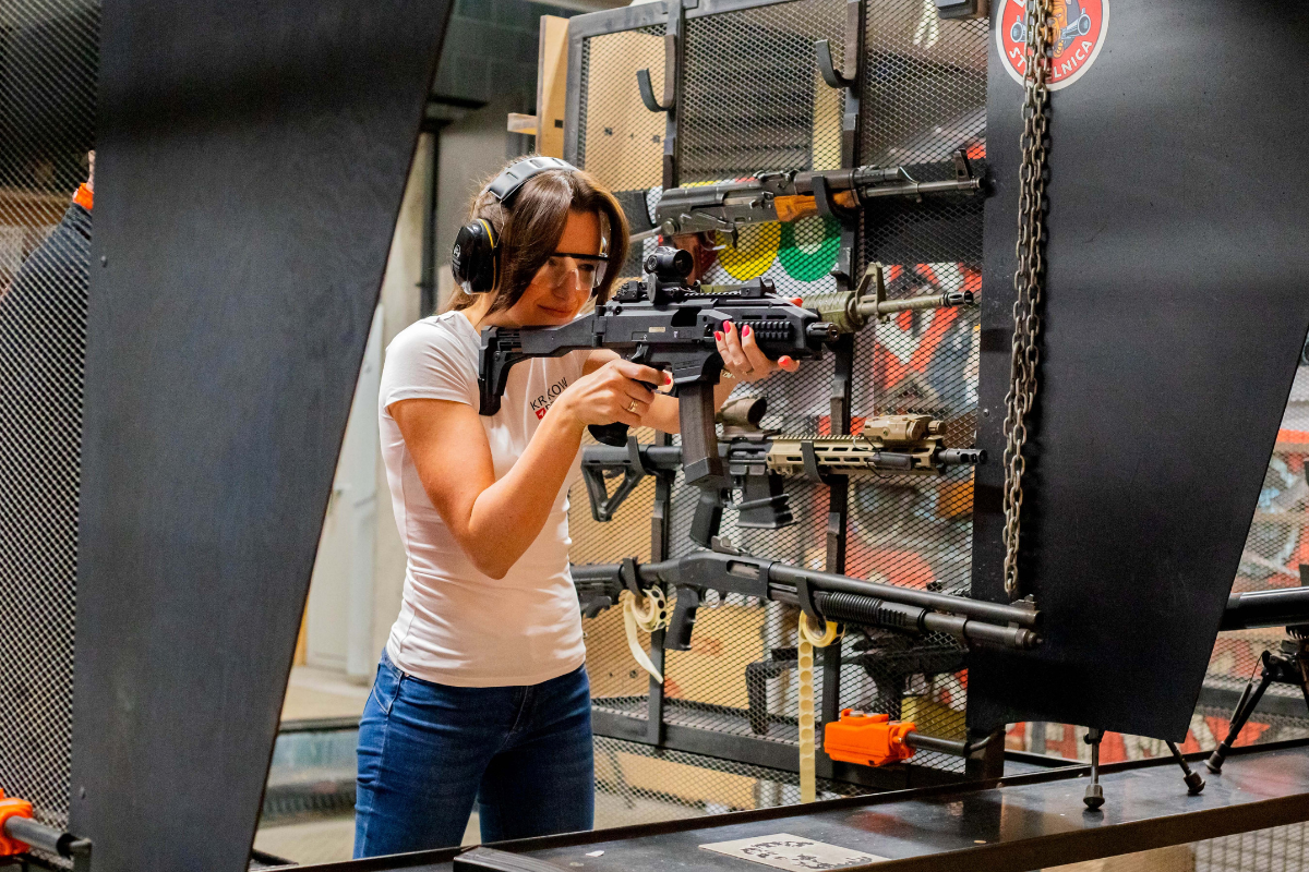 Woman aiming a carbine rifle at the indoor shooting range in Krakow during a shooting tour.