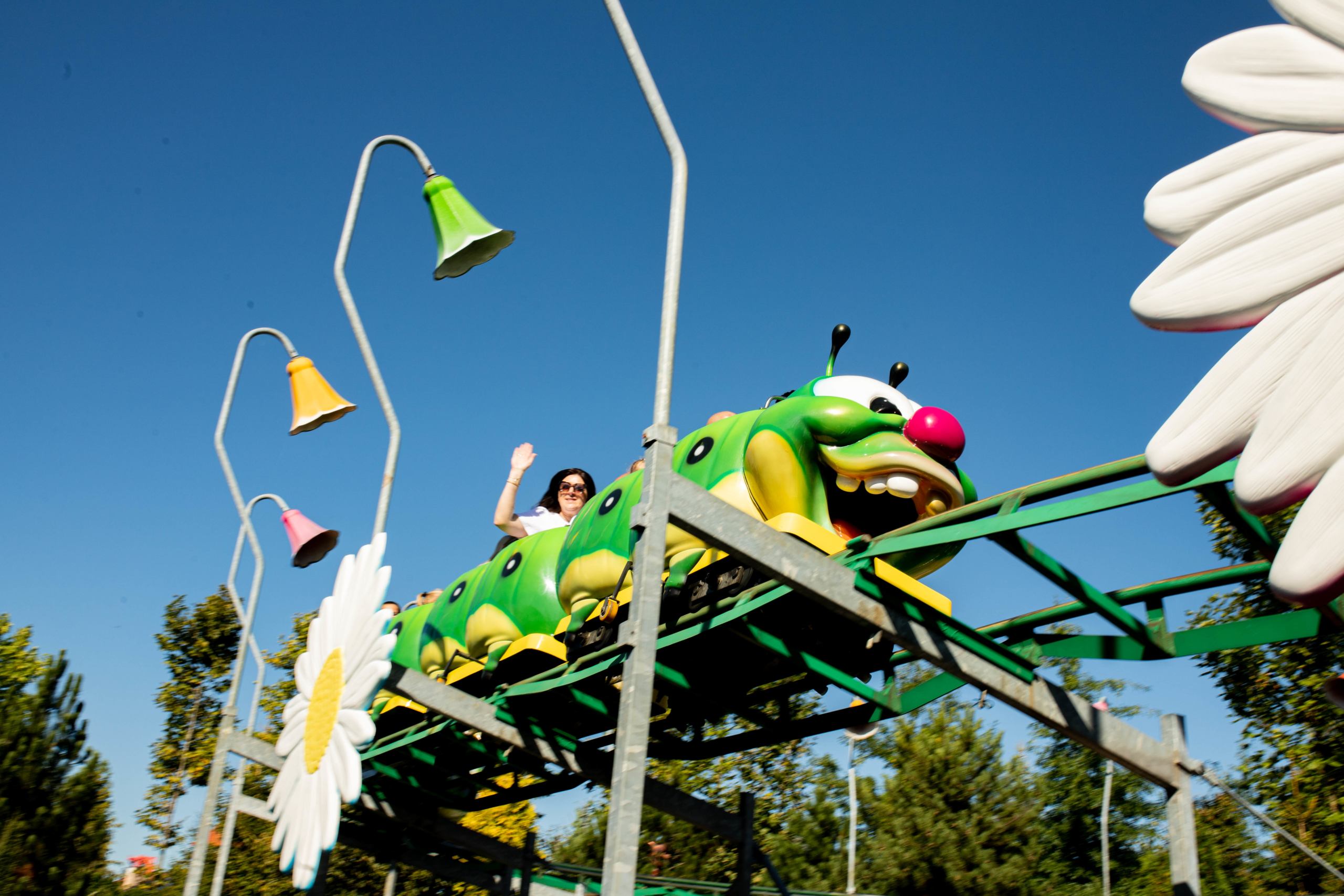 Caterpillar coaster for kids - Tour with KrakowDirect Caterpillar-themed kids roller coaster ride at Energylandia with colourful lamps and large daisy decorations.