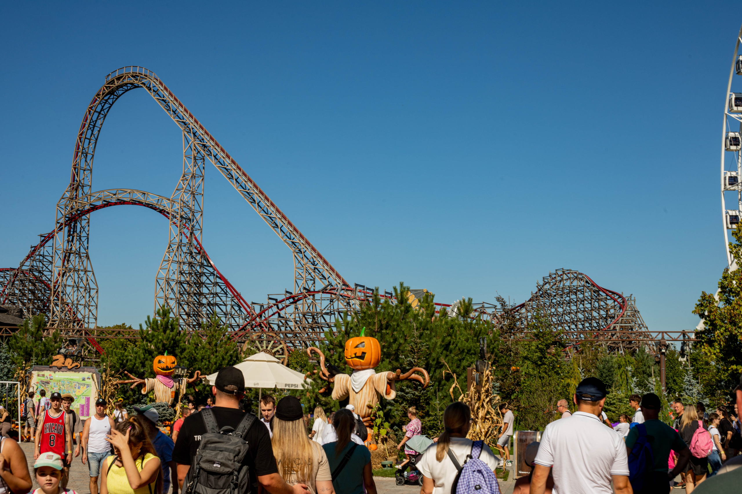 Seasonal crowd day at Energylandia (Halloween vibe) Energylandia view with a roller coaster and Ferris wheel, seasonal pumpkin decor.