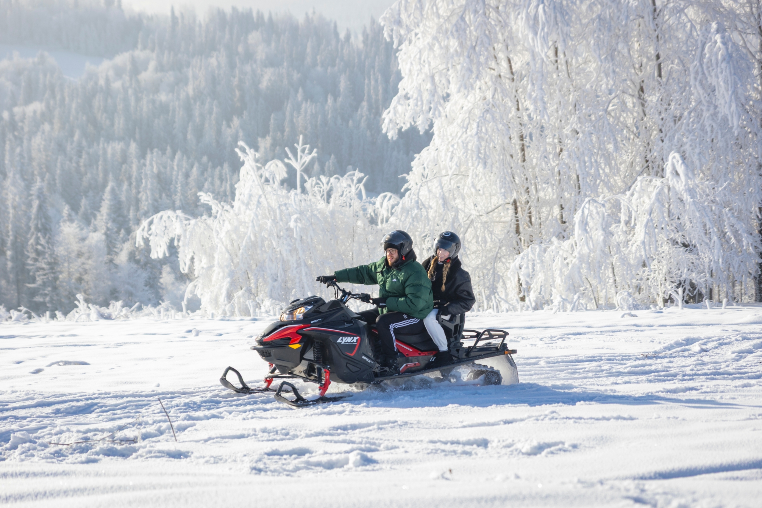 zakopane-snowmobile-tour-ride Two people riding across a snowy field on a Zakopane Snowmobile Tour